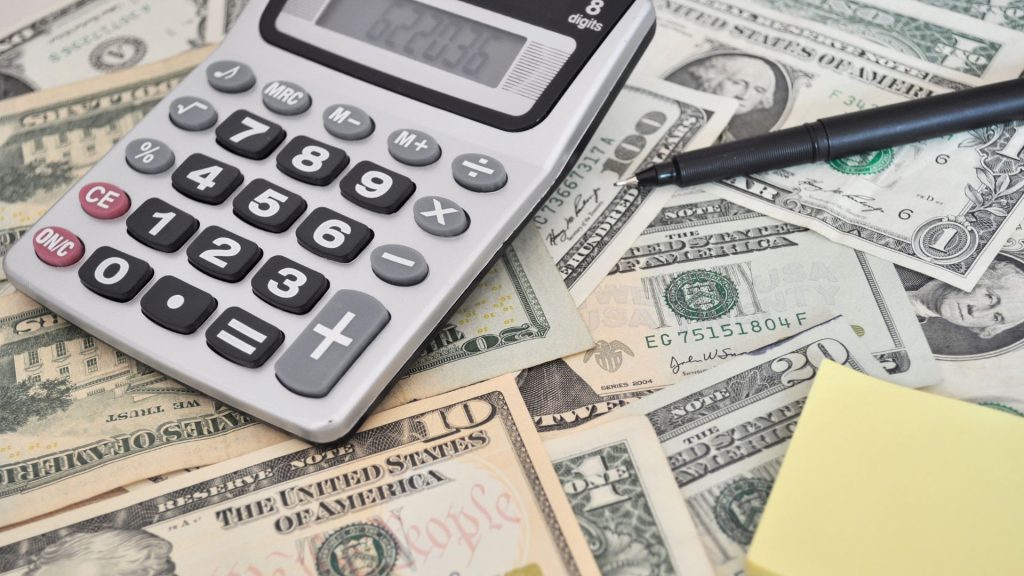 a calculator on top of some dollars scattered on a table