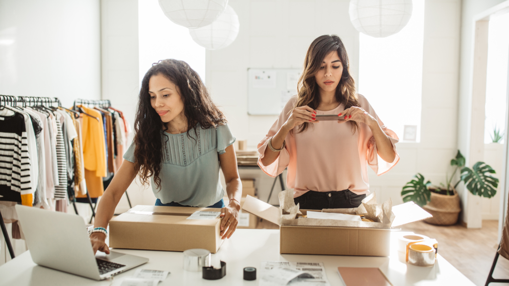 Two small business owners work together to prepare packages, showcasing teamwork and strategies to prevent funding mistakes and personal credit damage.