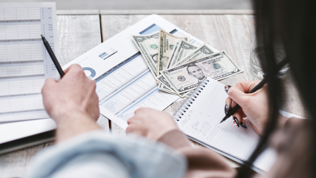 Two people analyzing financial statements and cash while planning business debt strategy.