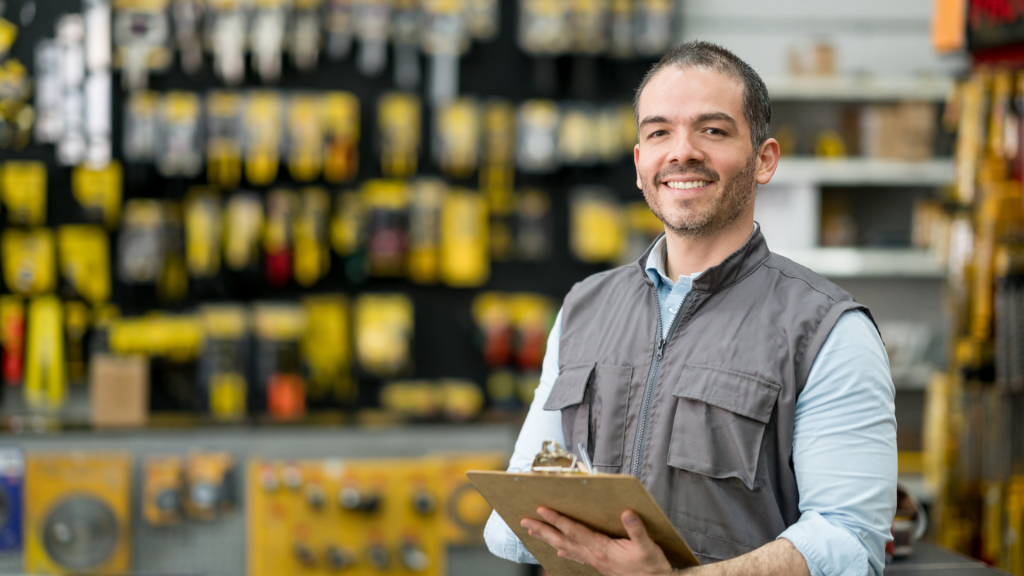 Confident small business owner smiling while holding a clipboard inside a hardware store.