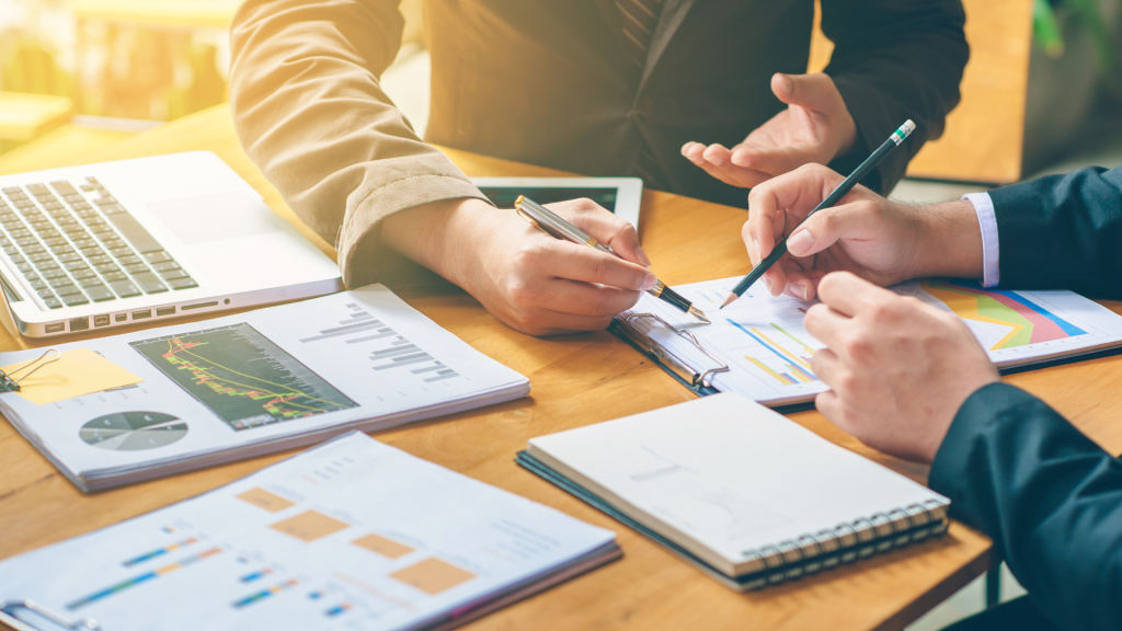 Hands of two professionals analyzing a success scan report with financial charts and graphs.