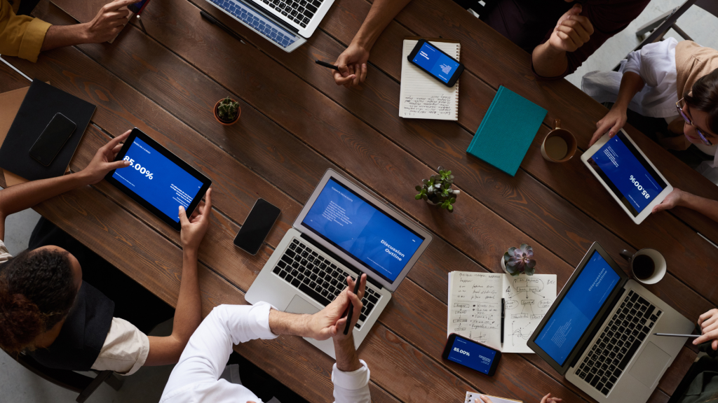 Diverse team of professionals analyzing Success Scan business assessment results on digital tablets and laptops.