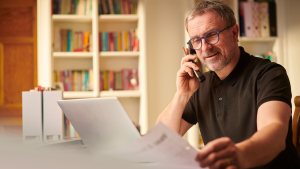 Business owner reviewing credit documents on phone with financial advisor